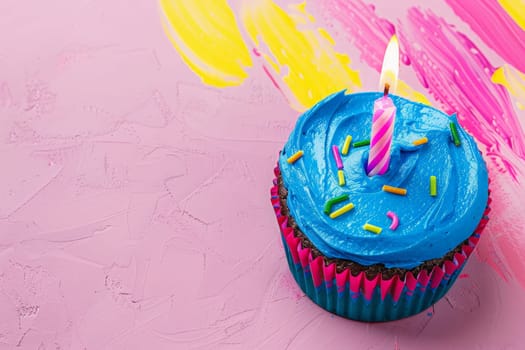 A cupcake with blue frosting has a lit candle on top, ready to make a wish.