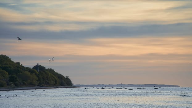 Sunset, illuminated sea. Sandy beach in the foreground. Light waves. Poel island on the Baltic Sea. Nature photo from the coast