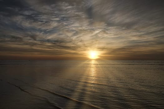 Sunset on the beach by the sea. Gentle waves. Sparkling water. The island of Poel on the Baltic Sea. Nature photo from the coast