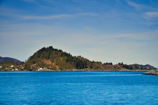 Fjord with mountains on horizon. Water glistens in the sun in Norway. Landscape photo from the north