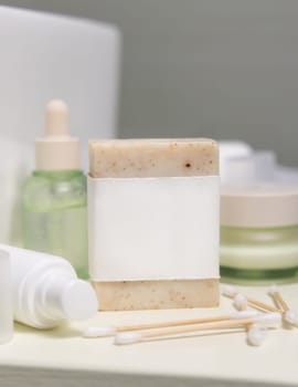 Soap bar with blank label near cosmetics and personal care products close up, cosmetic packaging mockup, copy space. Natural homemade organic hygiene products