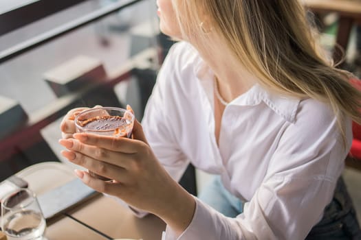 Gen z blonde woman drinks hot chocolate in summer cafe. Tasty beverage and break