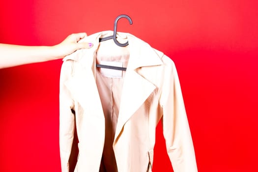 Shot of young woman hand throwing her outwear dress in the trash isolated on red background
