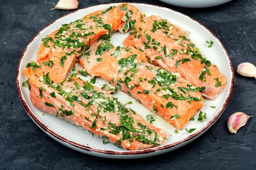Raw uncooked salmon or trout fillet fish in garlic green marinade.