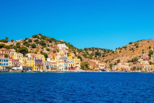 SYMI, Greece - JUN 03, 2021. The harbour of Symi town with the districts of Chorio and Gialos is one of the most beautiful and romantic in the whole Aegean. Colourful mansions stretch up the steep slopes.