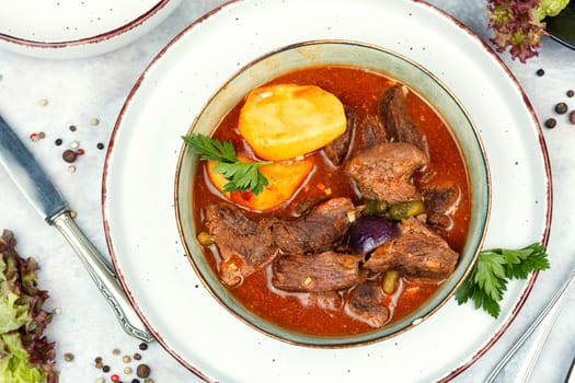 Appetizing goulash made from venison meat, meat goulash or soup with potatoes in a bowl.