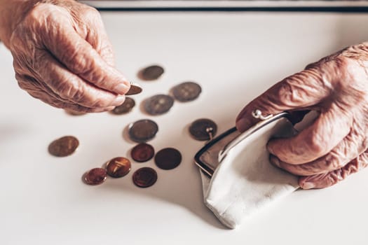Detailed closeup photo of elderly 96 years old womans hands counting remaining coins from pension in her wallet after paying bills. Unsustainability of social transfers and pension system.