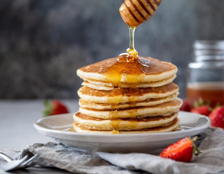 a stack of fluffy pancakes with maple syrup drizzle