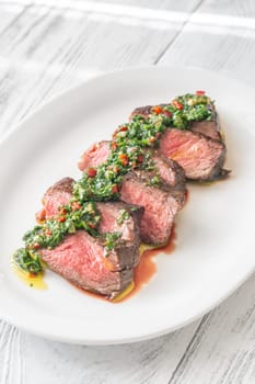 Portion of sliced strip steak with Chimichurri sauce