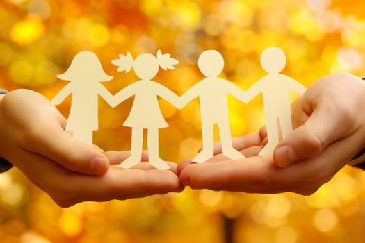 Two hands cradle a paper chain of diverse family figures, symbolizing unity and love against a glittering backdrop.