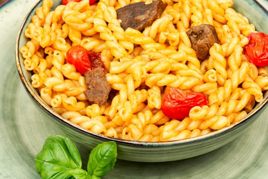 Delicious boiled and fried pasta with beef and vegetables on rustic wooden table.