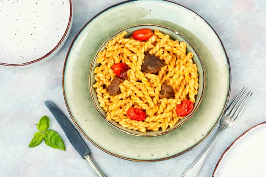 Delicious boiled and fried pasta with beef and vegetables on rustic wooden table.