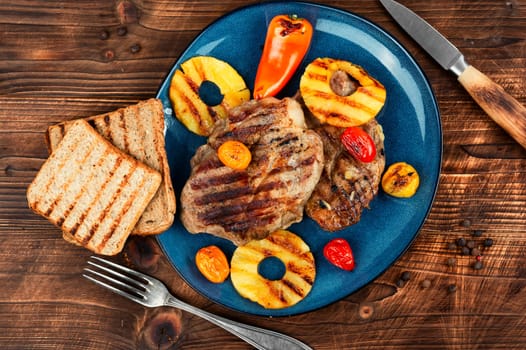 Tasty grilled meat,roasted with pineapple. Grilled steak and ananas on wooden table.