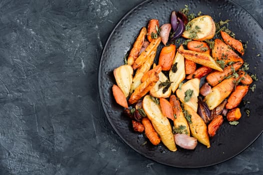 Vegan garnish of baked parsnip root, red onions, carrots and garlic. Roasted root vegetables. Space for text.