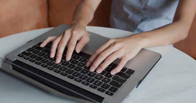 Woman types on laptop computer at home