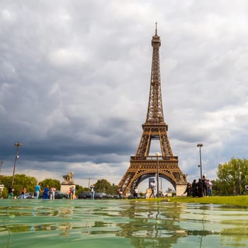 Paris, France - August 29 2023: Tourists and Eiffel tower seen from Trocadero Fountains in a cloudy day. Squared photography taken in Paris.