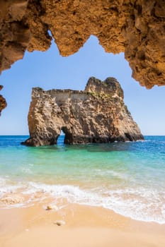 Small, heavenly and difficult to access beach vertically photographed from inside a cave, near Portimão in the Algarve region of Portugal