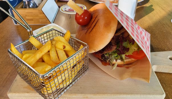 Traditional homemade burger on baking paper with french fries