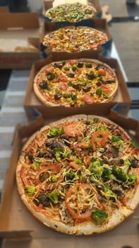 Line of Italian pizza portions with a variety of trimmings displayed in a panorama banner or header on slate for menu advertising