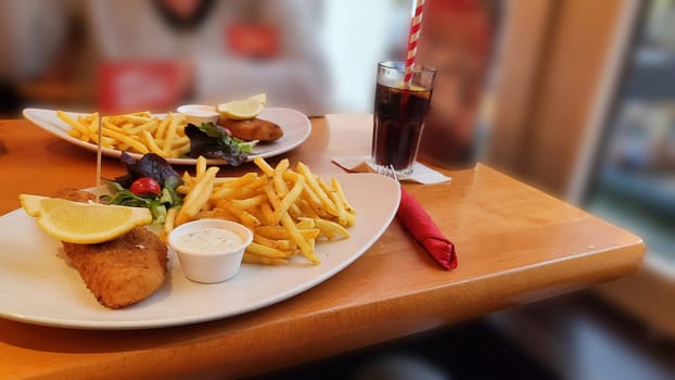 Fish and chips. Close up of crispy breaded deep fried Alaska pollock fillets in breadcrumbs served with tartar sauce french fries and lemon