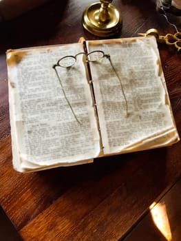 Old wire glasses isolated on blurred books background. Keep the perspective