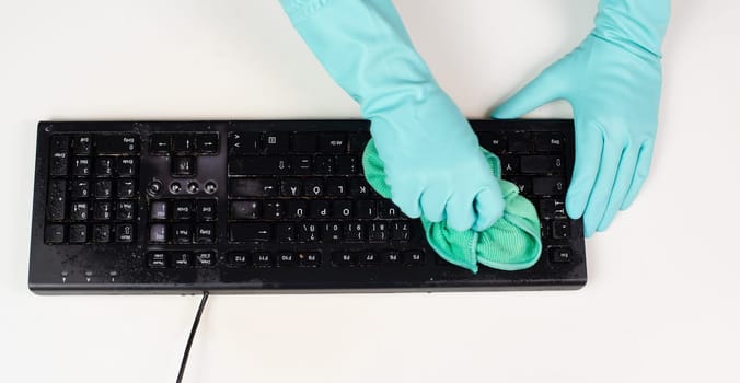 Cleaning computer keyboard in office with a wet wipe rag, dusty and dirty electronic, housework