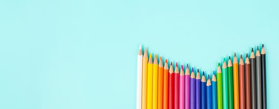 Color pencils collection in a row, back to school, drawing supplies, blue background with copy space