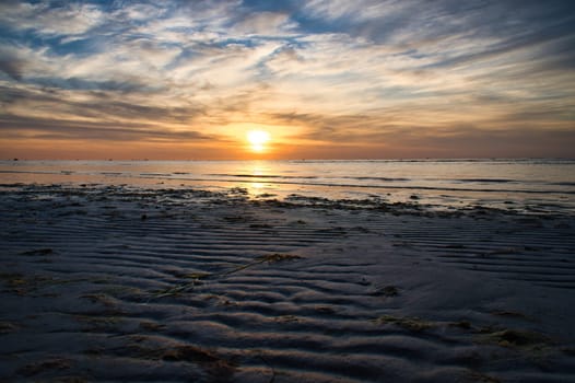 Sunset, illuminated sea. Sandy beach in the foreground. Light waves. Poel island on the Baltic Sea. Nature photo from the coast