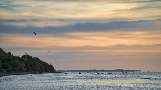 Sunset, illuminated sea. Sandy beach in the foreground. Light waves. Poel island on the Baltic Sea. Nature photo from the coast