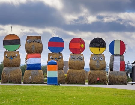 Funny figures made of straw bales on the background of a winter forest and field