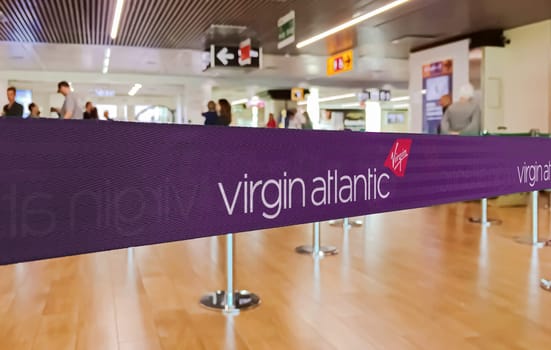 London, UK, May 14 2024  Close view of a Virgin Atlantic branded ribbon at a check-in counter, highlighting the airline’s distinctive purple branding and logo.