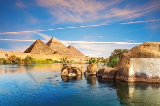 Sunset over the Nile river with ancient rocks on the way to pyramids, Aswan, Egypt.