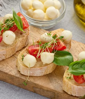 Round mozzarella, cherry tomatoes and microgreens on a piece of white bread, a healthy sandwich, close up