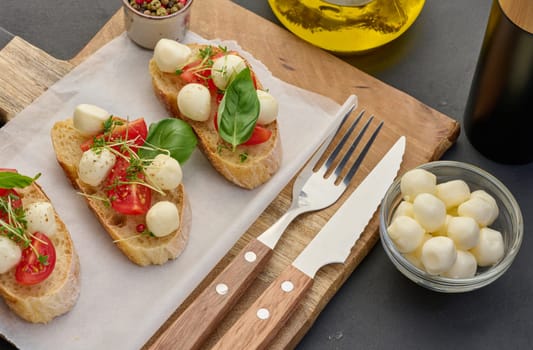 Round mozzarella, cherry tomatoes and microgreens on a piece of white bread, a healthy sandwich
