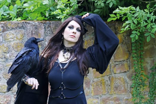 A woman dressed as a witch with a large raven on her hand