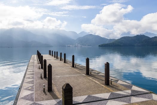 Large blue lake surrounded by mountains with pier in the morning at sun moon lake of Taiwan