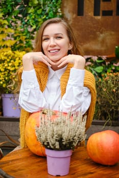 Satisfied smiling woman sitting at a table on the terrace with her chin on her hands