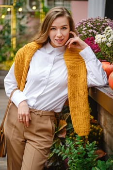 Outdoor portrait of cute lovely woman at an autumn fair leaning on a wooden display table