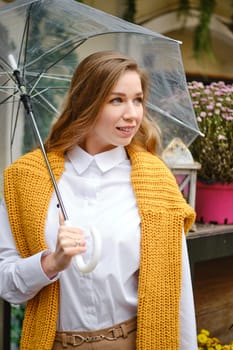 Autumn portrait of a young woman with a transparent umbrella