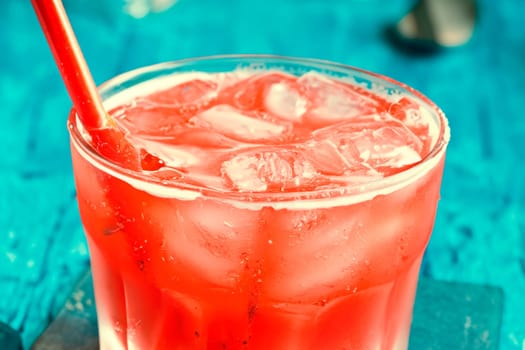 Summer refreshing red drink in a glass with a straw.