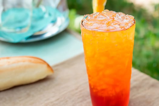 A glass of bright red-orange cocktail on the table on the terrace.