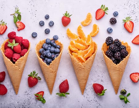 Waffle cones with different types of fruit on a light background