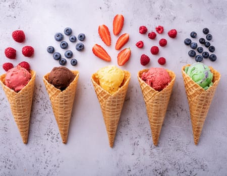 Waffle cones with different types of fruit on a light background