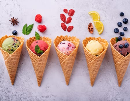 Waffle cones with different types of fruit on a light background