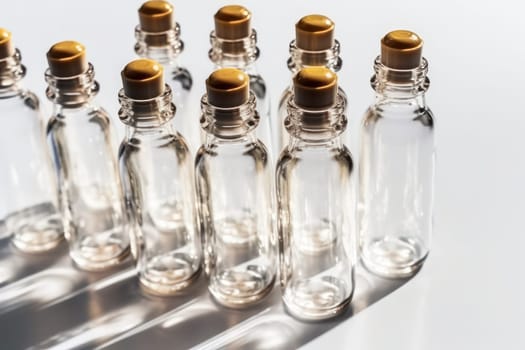 A neatly arranged row of clear glass bottles with wooden caps, casting long shadows in bright light.