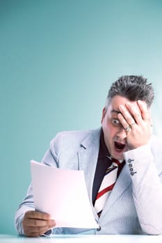 Shocked anchorman in grey suit covers his face, reacting to unbelievable news in the document he holds