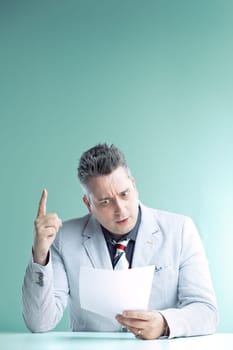 Engaged anchorman in light grey suit gestures emphatically while holding papers, his expression one of urgent revelation