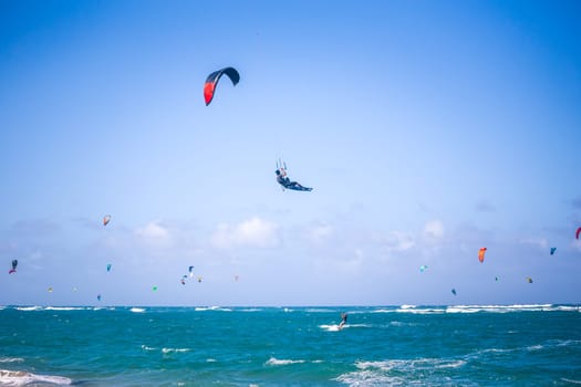 Kiteboarding. Fun in the ocean. Extreme Sport Kitesurfing. Kitesurfer jumping high in the air performing triks during kitesurfing session