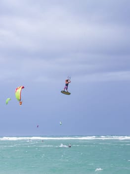 Kiteboarding. Fun in the ocean. Extreme Sport Kitesurfing. Kitesurfer jumping high in the air performing triks during kitesurfing session