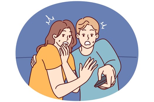 Frightened man and woman with TV remote control are shocked after watching scary movie with murders or monsters. Shocked couple gets scared while watching news on TV because of depressing forecasts